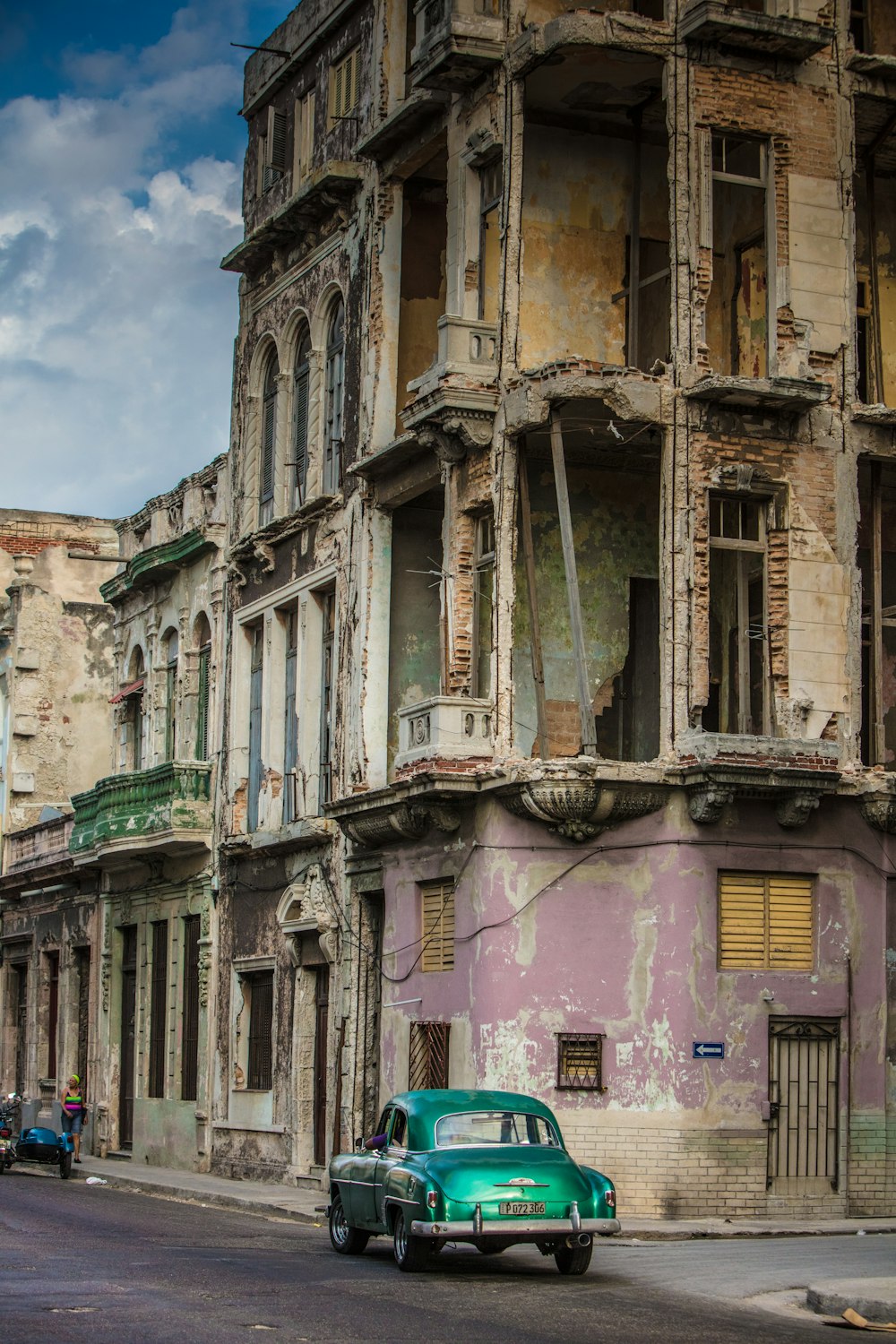 a green car parked in front of a building with peeling paint