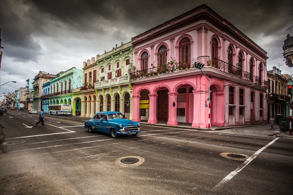 a car parked in front of a building with pink and blue paint