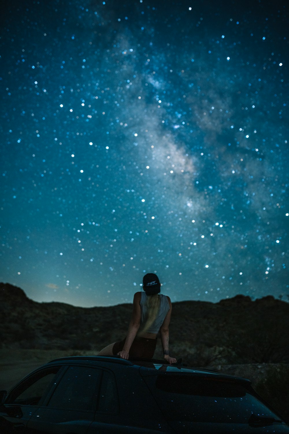 a man sitting on a car in front of a starry sky