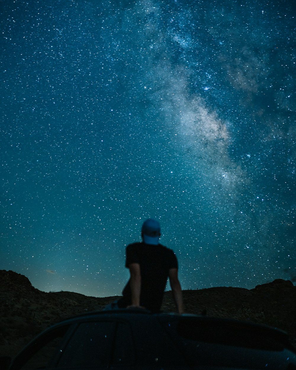 a person sitting on a rock looking at the stars in the sky