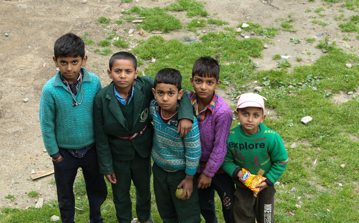 A group of smiling children posing outdoors, celebrating National Volunteer Week with colorful banners and balloons.
