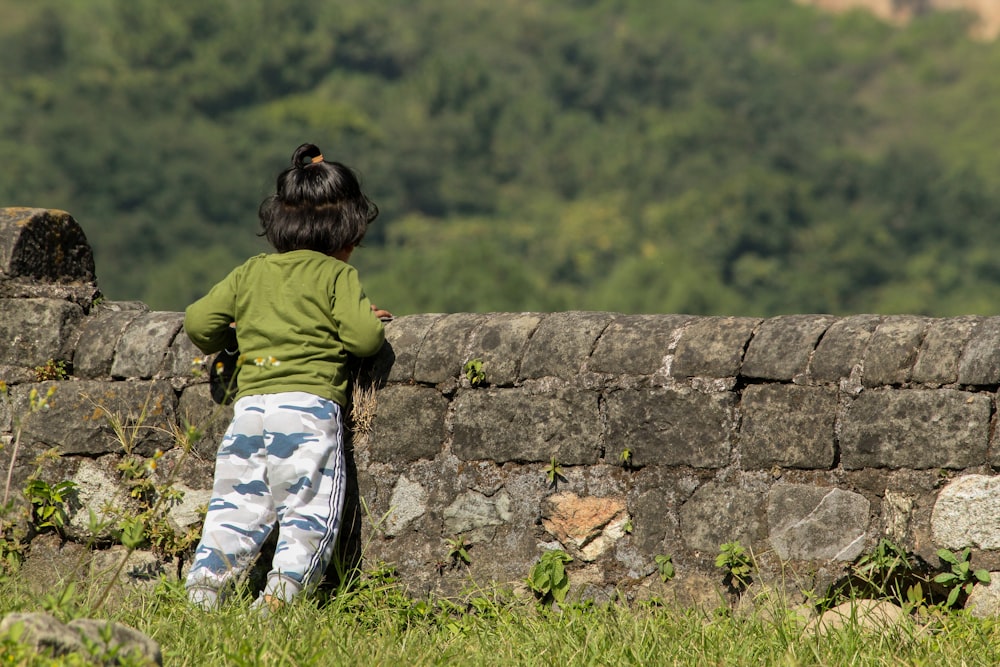 a child walking on a stone wall