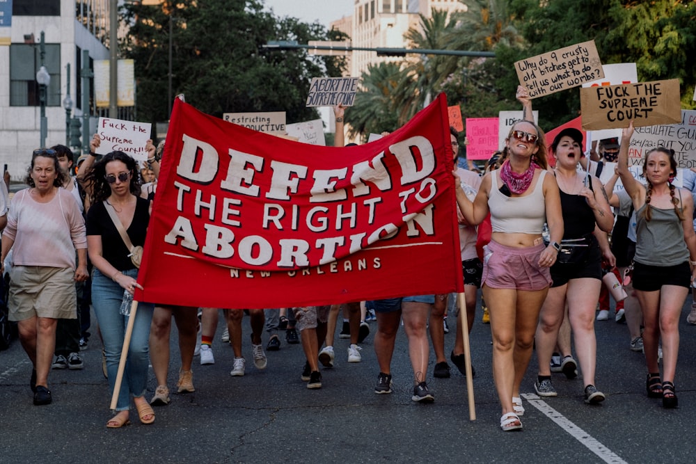 a group of people marching with a red sign