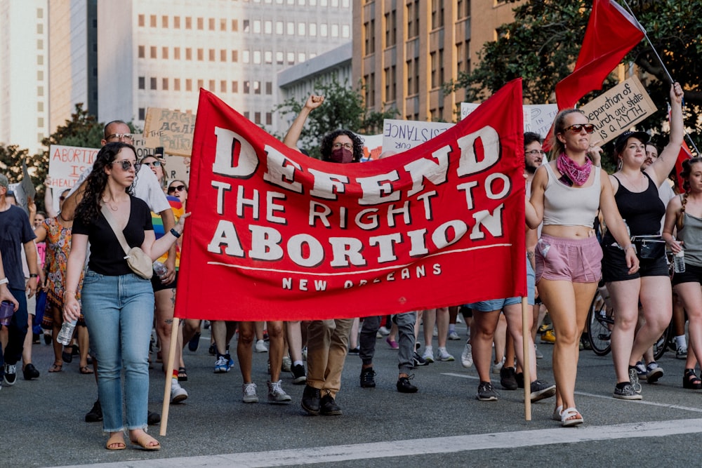 a group of people marching with a red sign