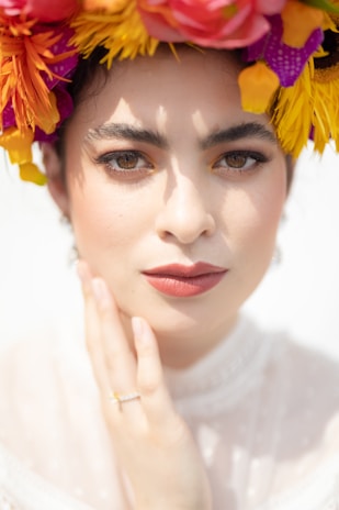 Close-up of a woman with striking eyes and a gentle smile, wearing a floral headpiece.