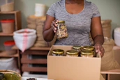Close-up of hands packing dairy essentials into boxes for shipment.