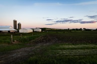 Sunset over a peaceful farm with barns and silos.