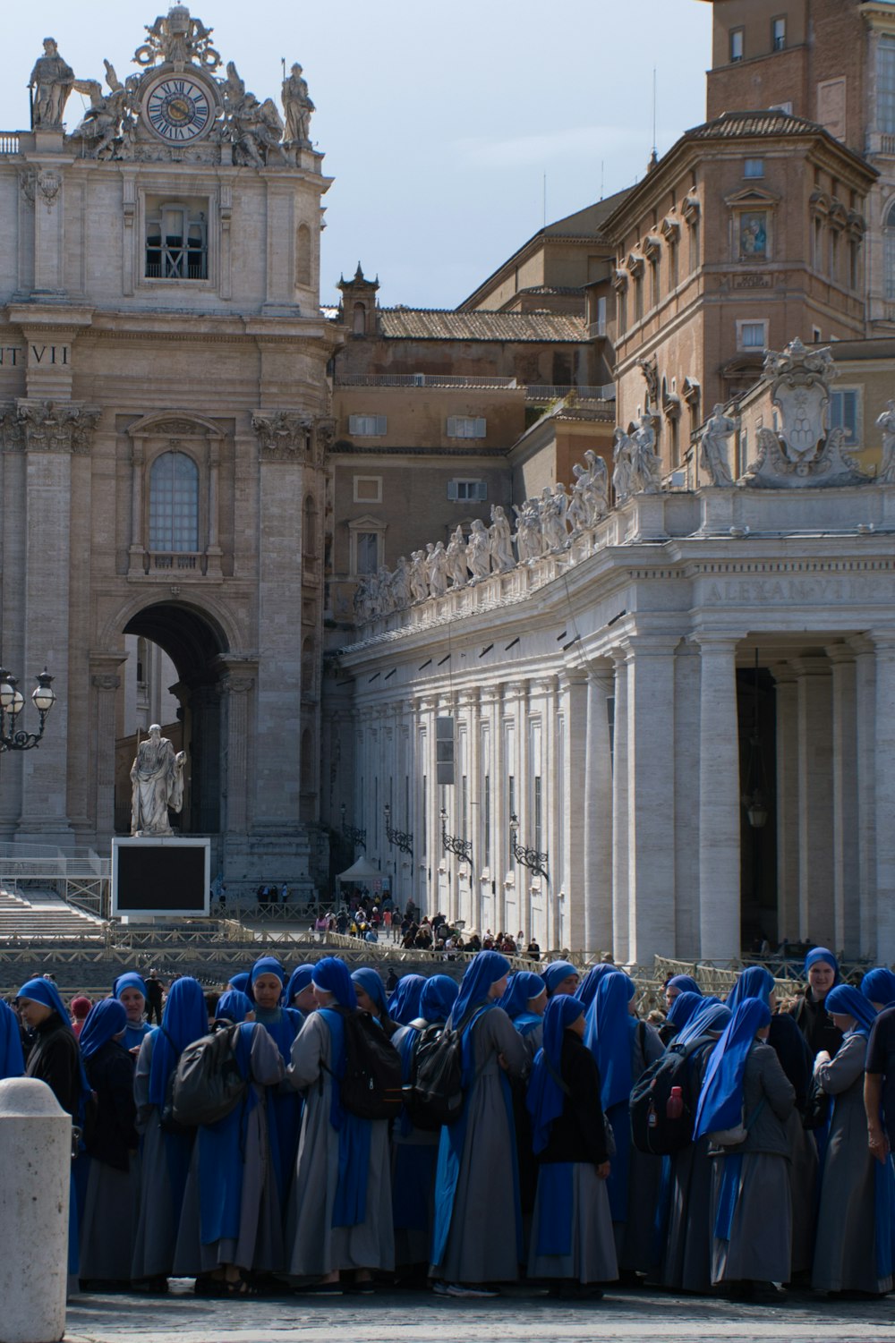 a group of people in blue robes standing in front of a building