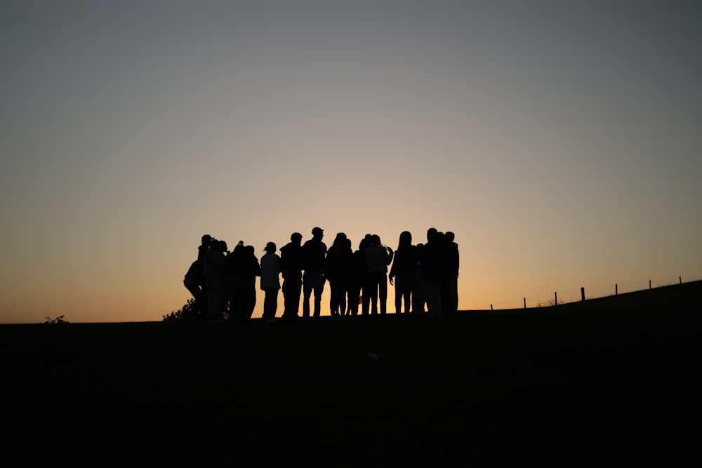 a group of men standing in front of a sunset