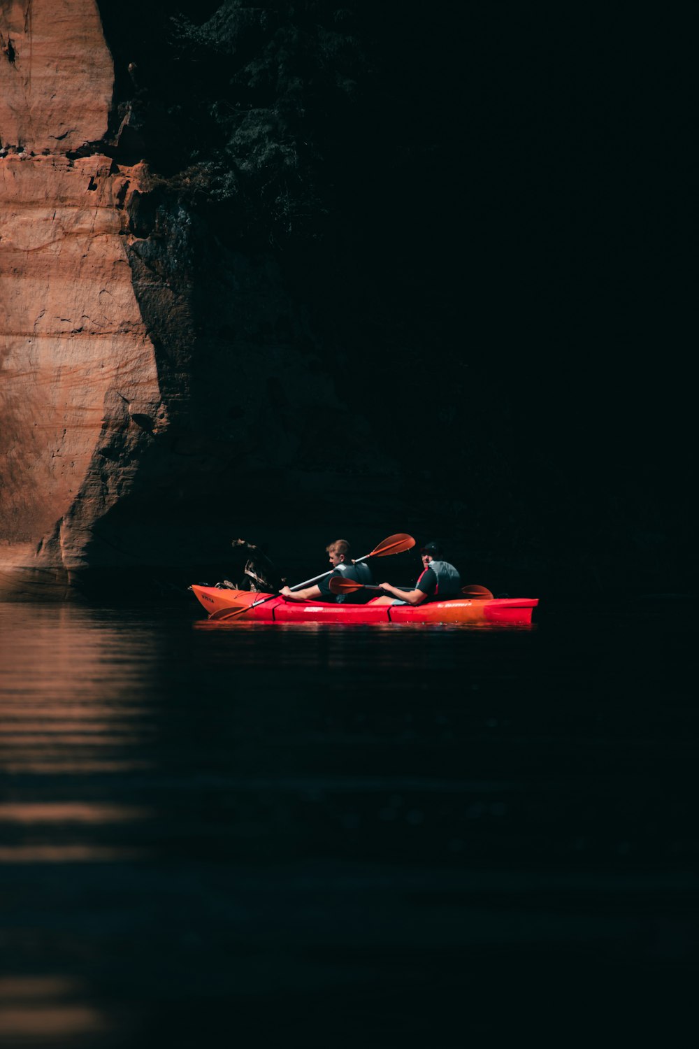 a man and woman in a kayak in a dark cave