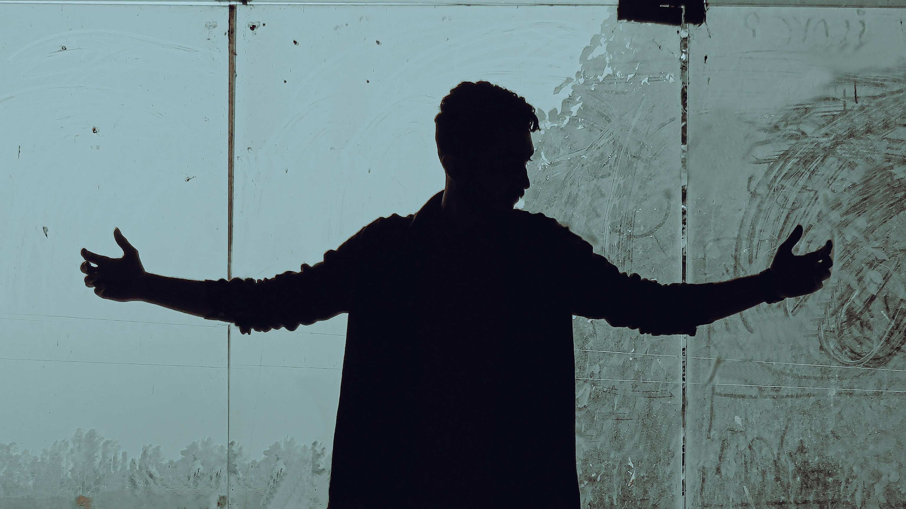 a man standing in front of a white wall with his hands up