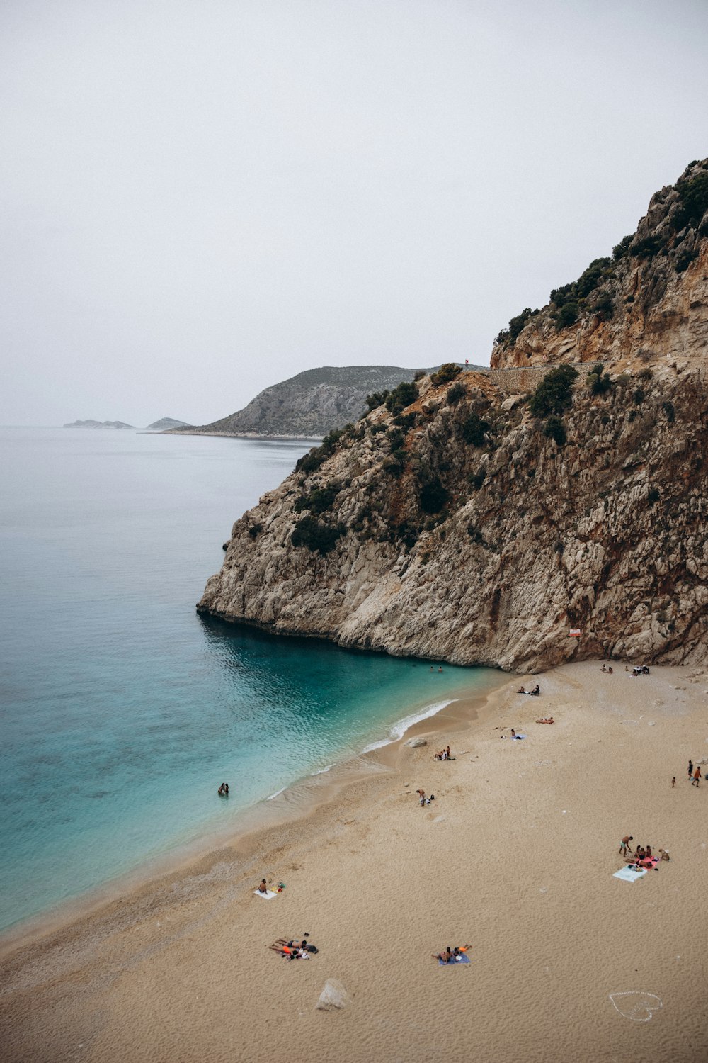 a beach with people on it by a cliff