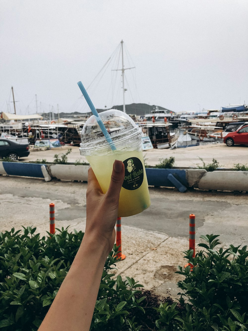 a hand holding a plastic cup with a straw and a white substance