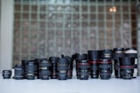 An array of different camera lenses displayed on a table.