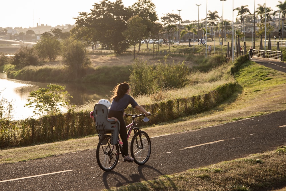 a person riding a bicycle on a road with trees and grass