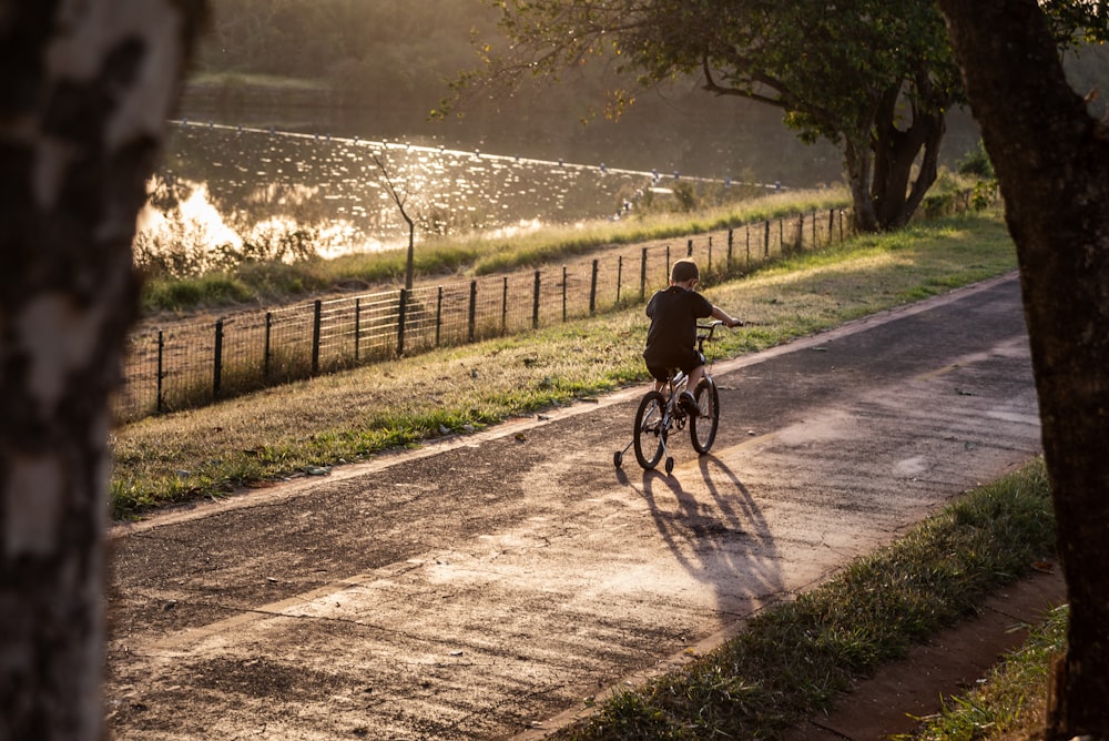 a person riding a bicycle on a path by a fence and trees