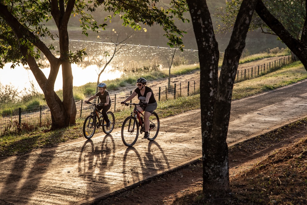 two people riding bikes on a path