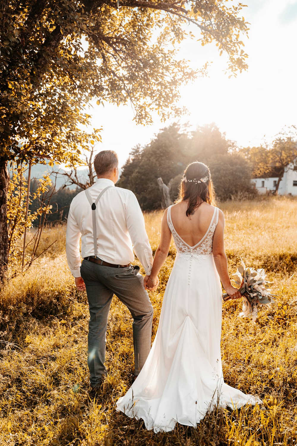 a man and woman walking down a path in a field of yellow flowers