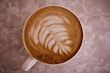 A steaming cup of artisanal coffee with latte art on top.