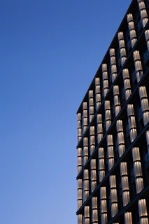 A modern architectural glass facade reflecting sunlight against a clear blue sky.