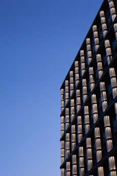 Modern glass curtain wall reflecting blue sky on a commercial building.