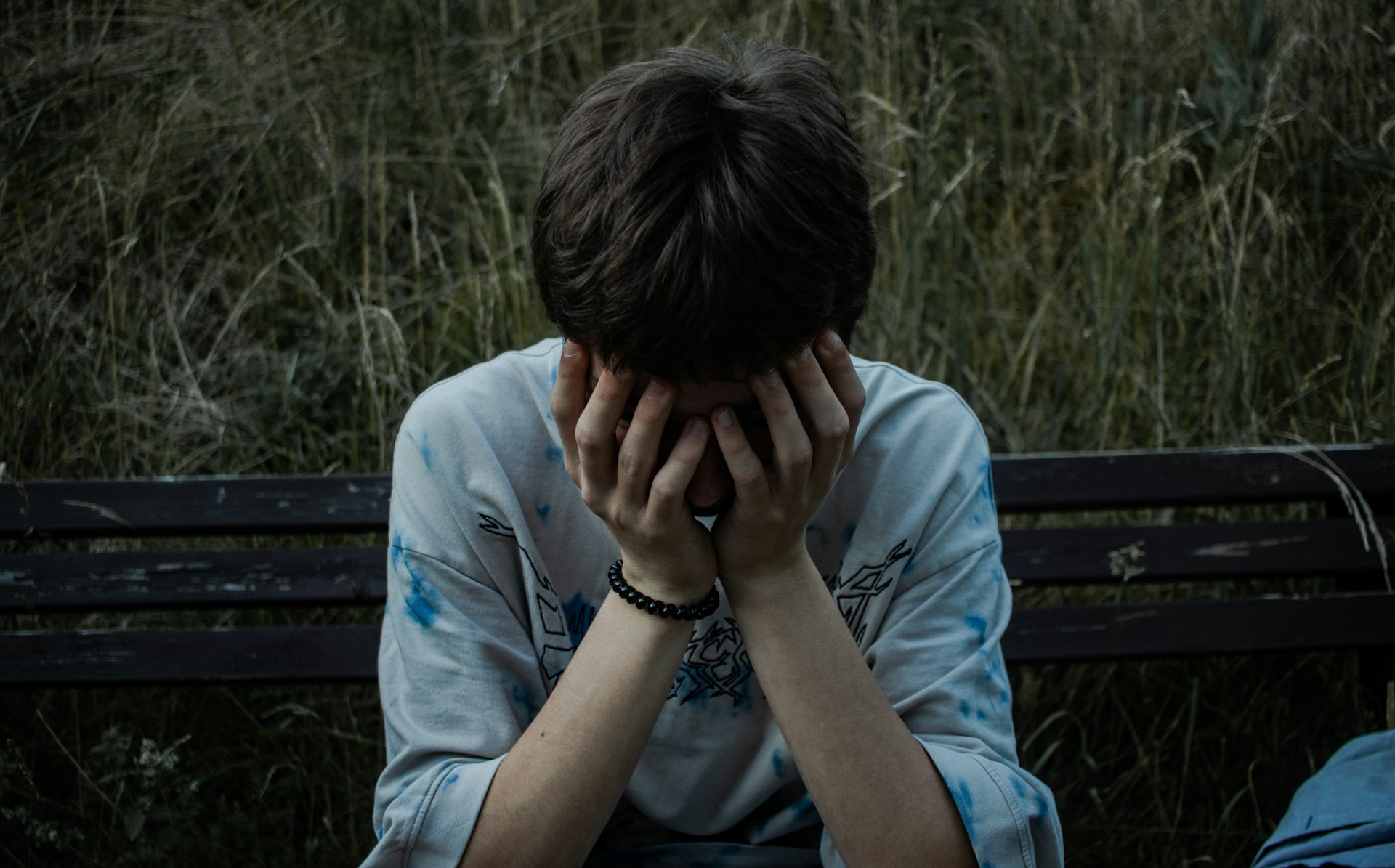 a person sitting on a bench with their hands on their face