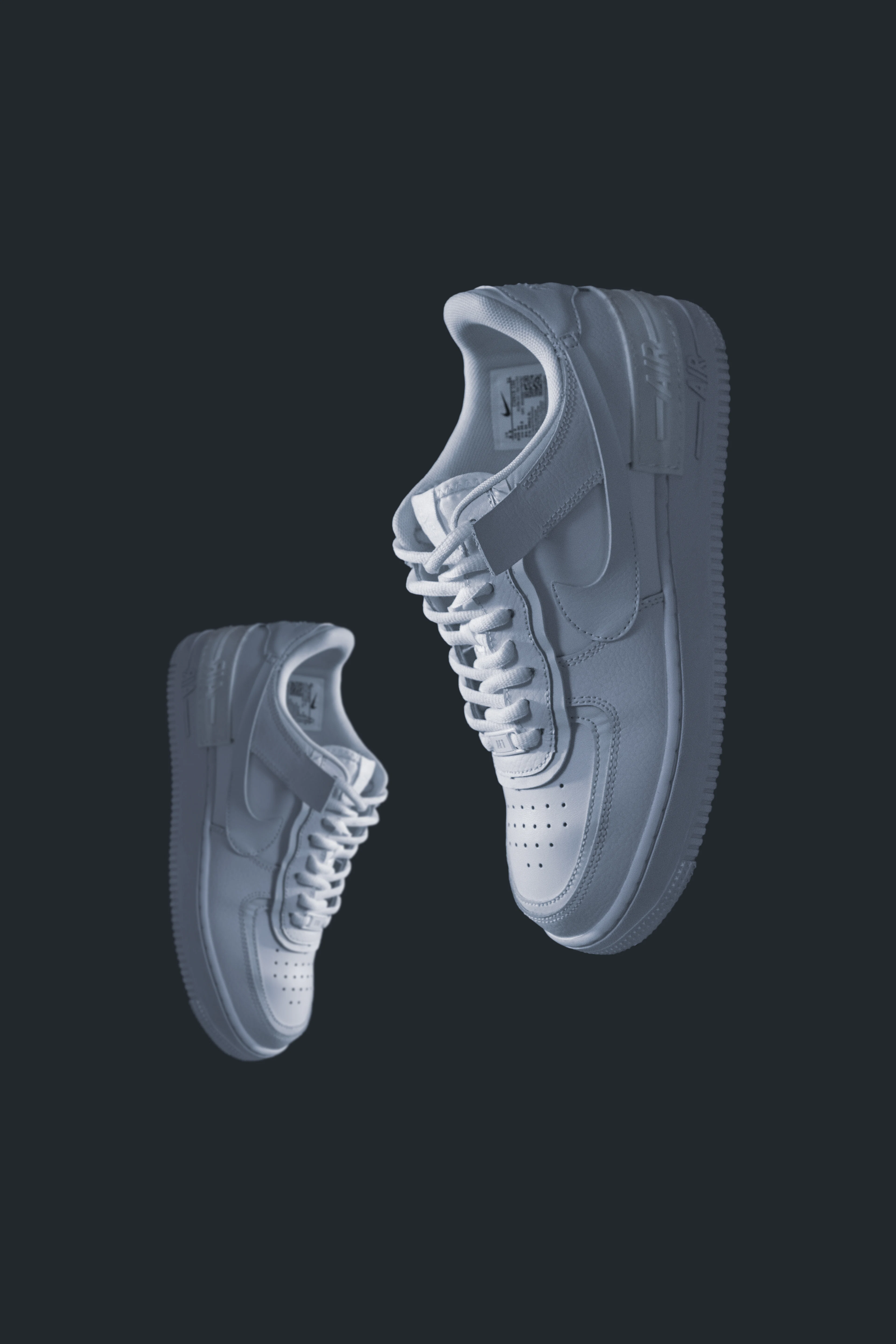 Pair of white leather court sneakers on a dark backdrop