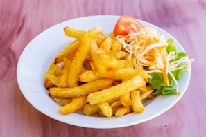 A compact air fryer with crispy fries inside, surrounded by fresh vegetables.