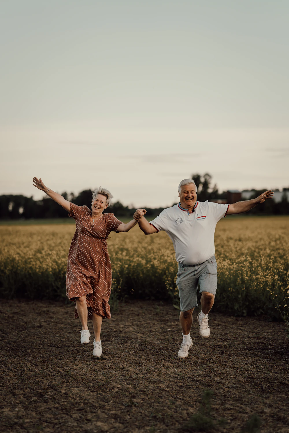 Casal de idosos correndo feliz por um campo
