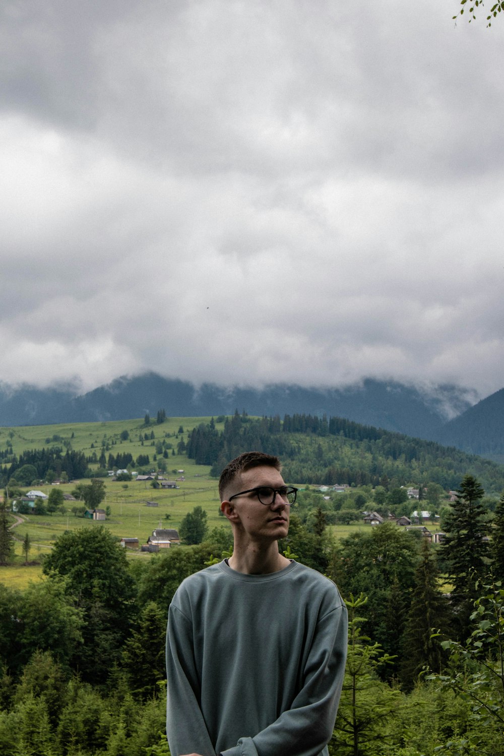 a man standing in front of a forest and a cloudy sky