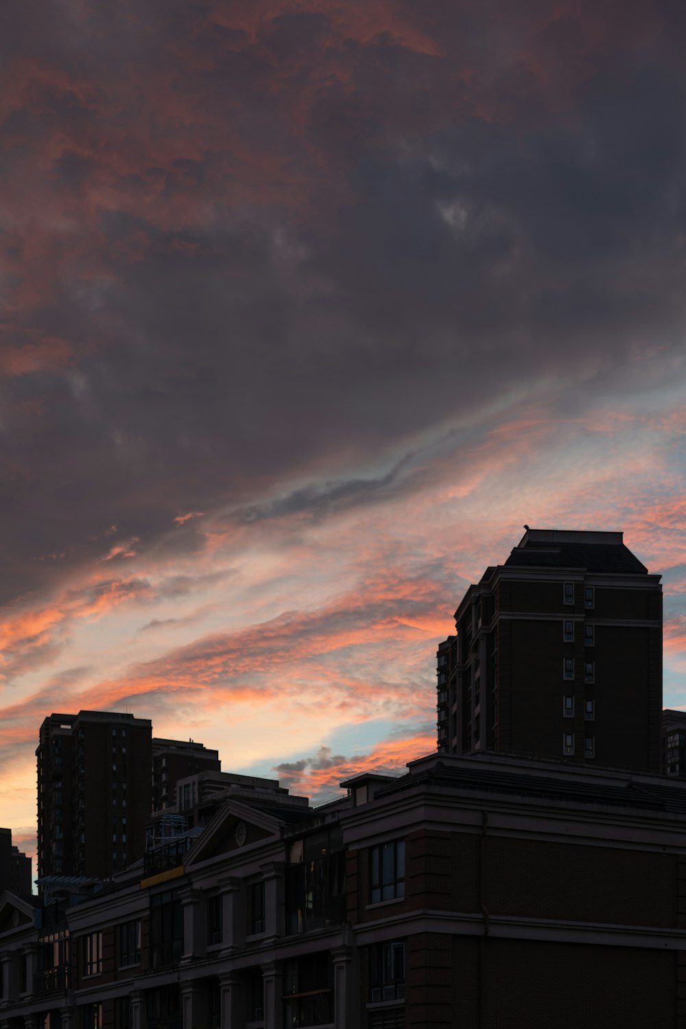 a group of buildings with a pink and purple sky above