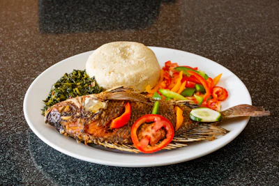 Close-up of a nutritious African meal featuring millet, leafy greens, and grilled fish.