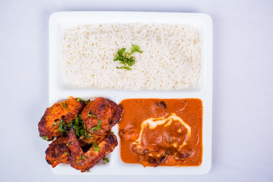 A beautifully arranged plate of chicken curry served with rice and salad.