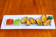 A colorful platter of loaded potato skins topped with cheese and bacon.