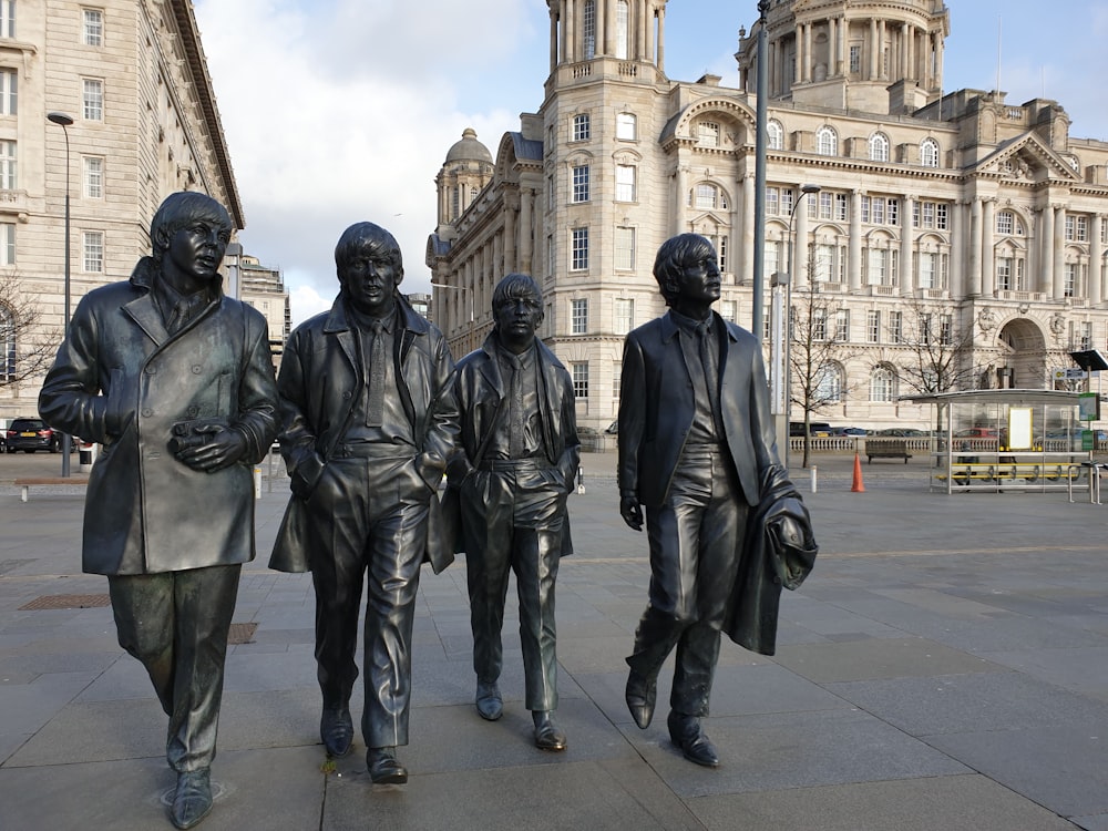 a group of statues of men in black suits in front of a building