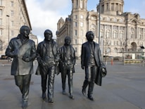 a group of statues of men in black suits in front of a building