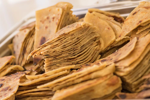 Hands breaking a crispy bhakhri, revealing its light, flaky layers inside.