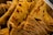 Stacks of folded, thin flatbreads with a flaky texture. The flatbreads have a golden brown hue with spots of darker browning, indicating they are well-cooked. Their layered appearance suggests they might be prepared with dough that has been rolled out and cooked on a hot surface.