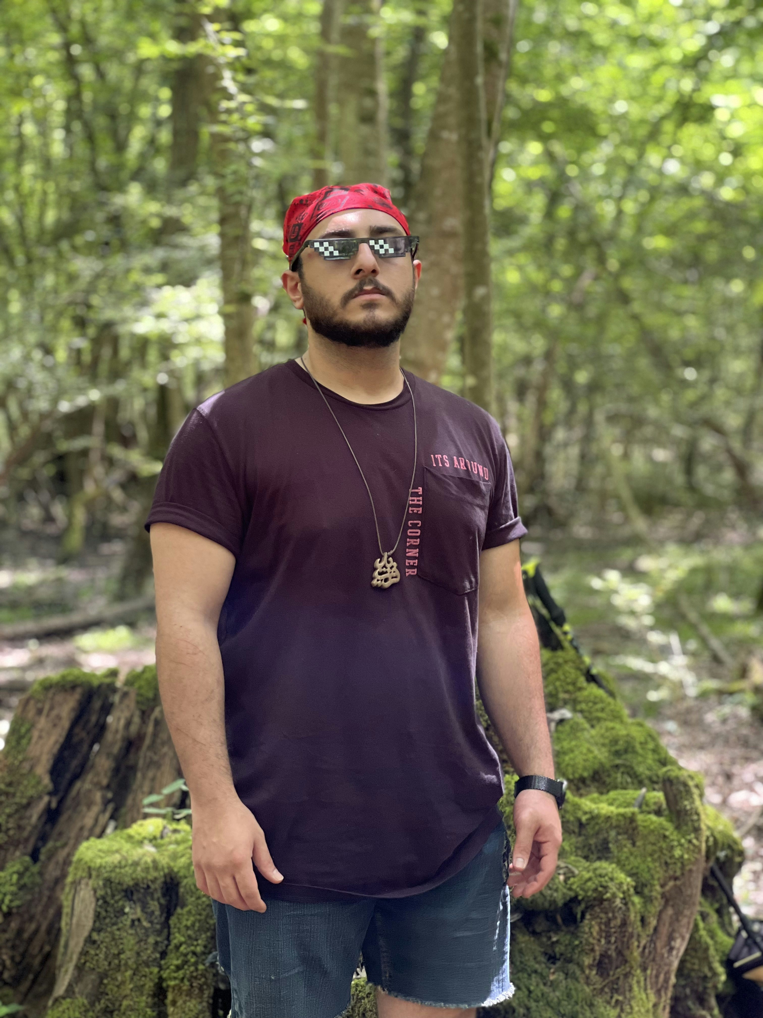 A man wearing a red hat and sunglasses standing in front of a rock wall ...