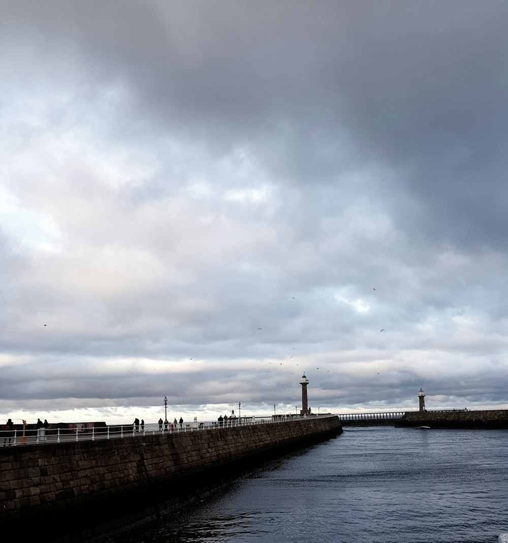 a body of water with a stone wall and a tower in the distance