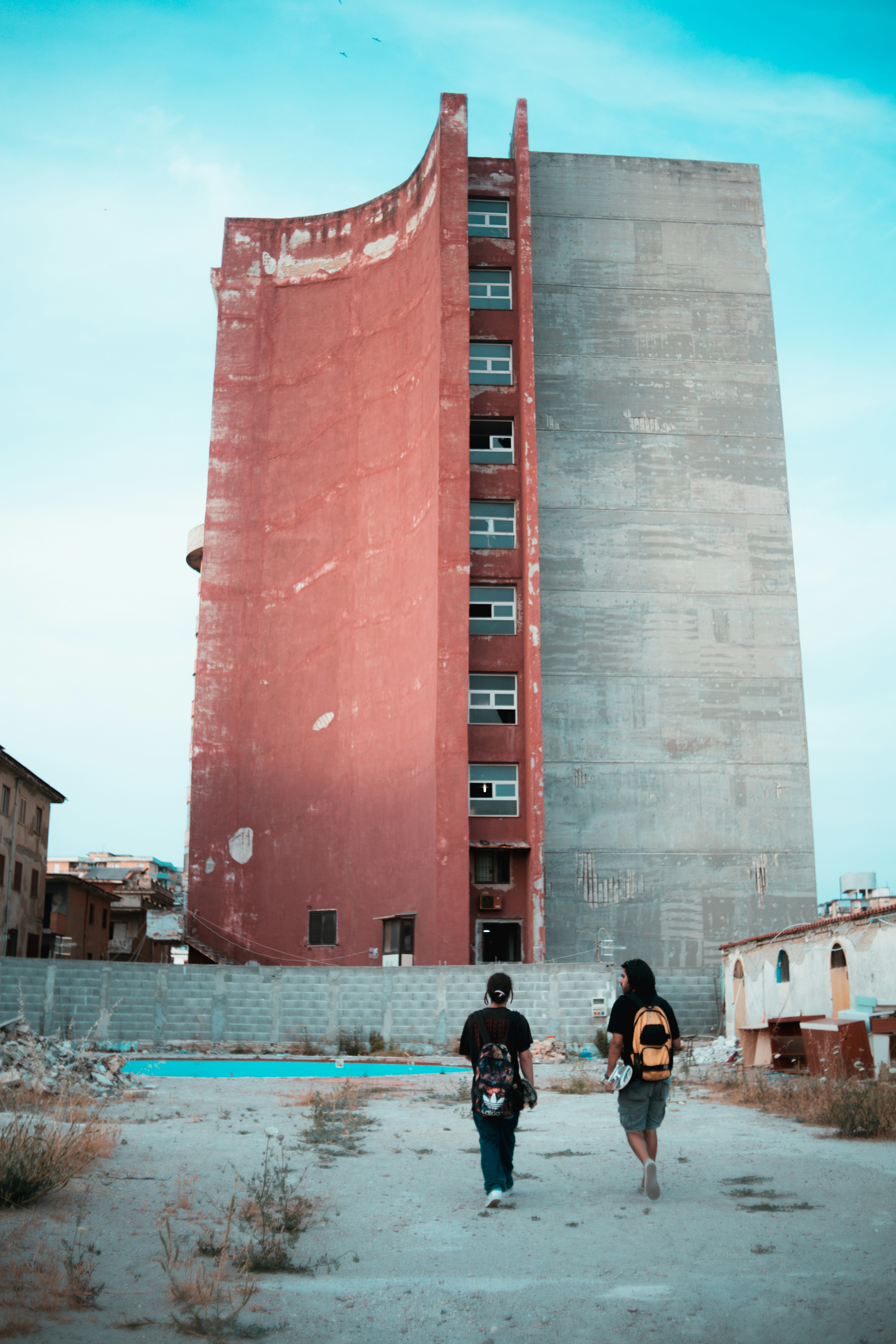 a couple of people walking towards a building that is falling apart