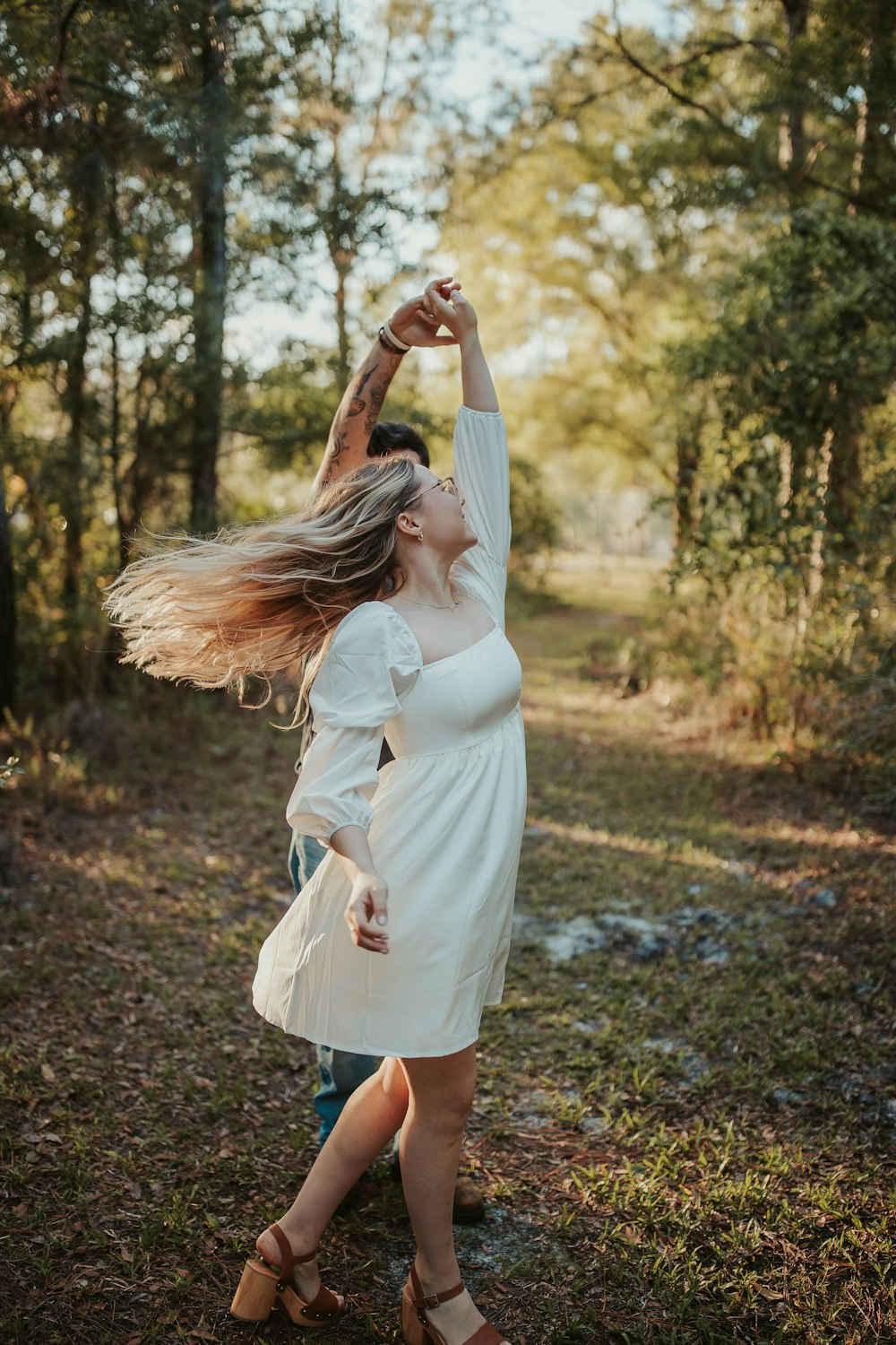 a woman with her hair in the air in a forest