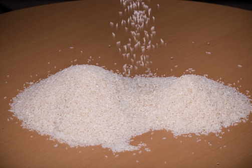 Golden grains of rice spilling gently from a woven basket onto a wooden surface.