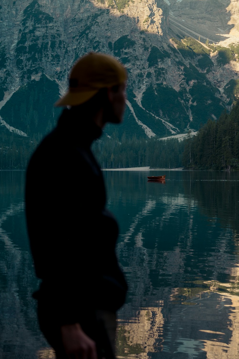 a man standing by a body of water with a mountain in the background