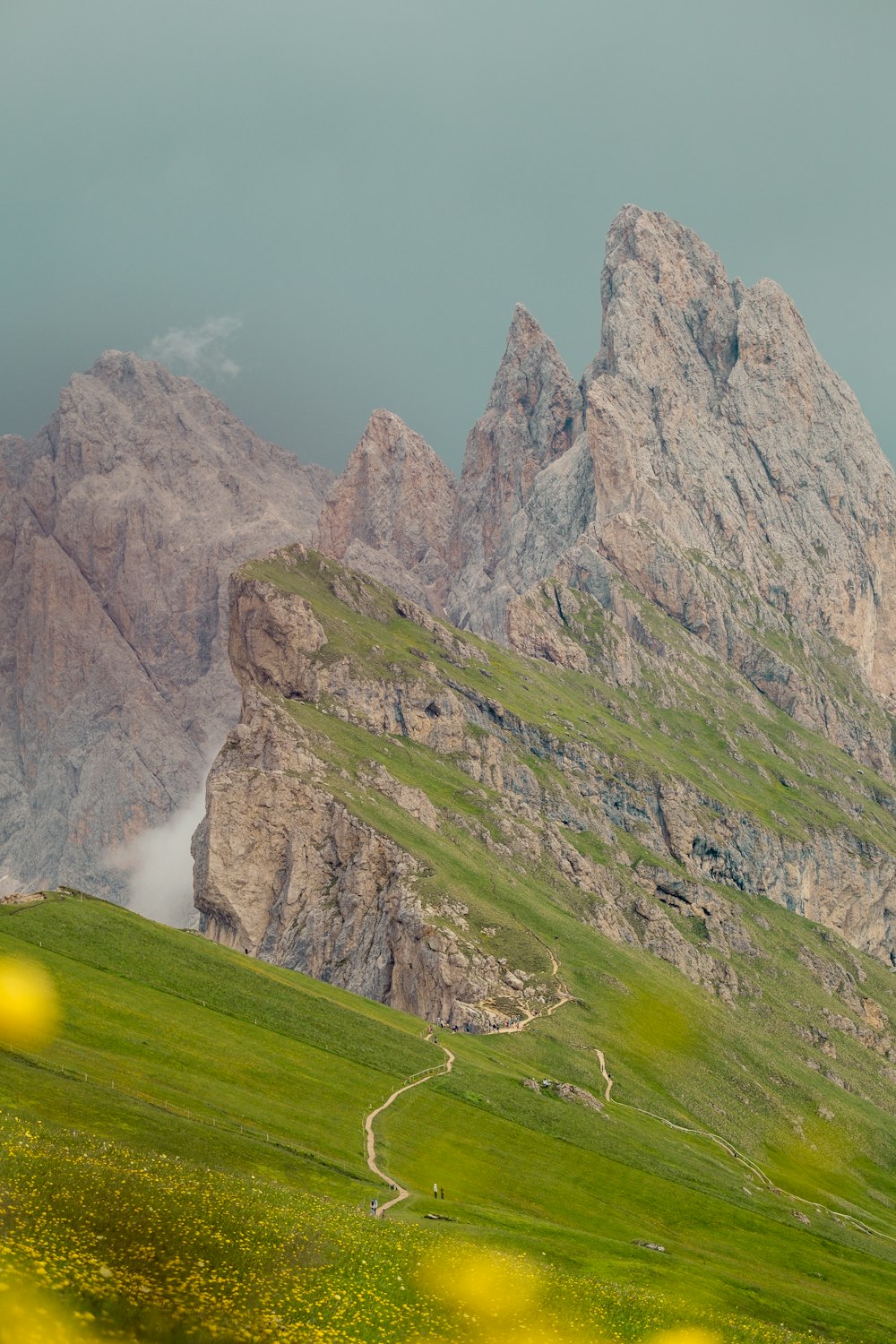 a grassy valley with a rocky mountain in the background