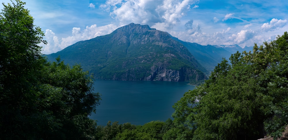 a body of water with trees around it and mountains in the back