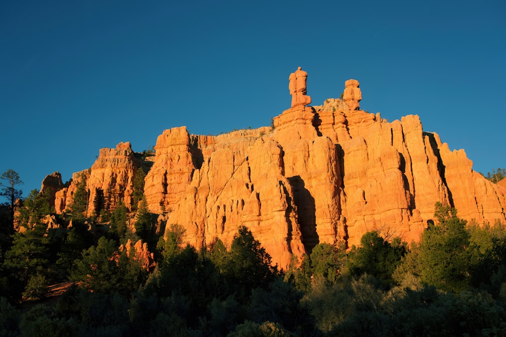 a rocky mountain with trees below