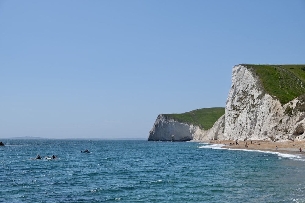 a beach with people and cliffs