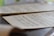A close-up view of sheet music resting on a surface, with musical notes and symbols clearly visible. The background is softly blurred, drawing attention to the details of the musical notation.