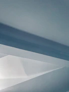 Abstract image featuring sleek geometric shapes in muted blue and sage green on an off-white background.